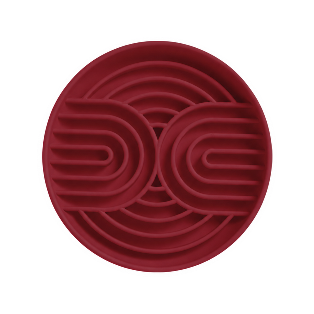 One red silicone slow feeder bowl with curved channels on a white background