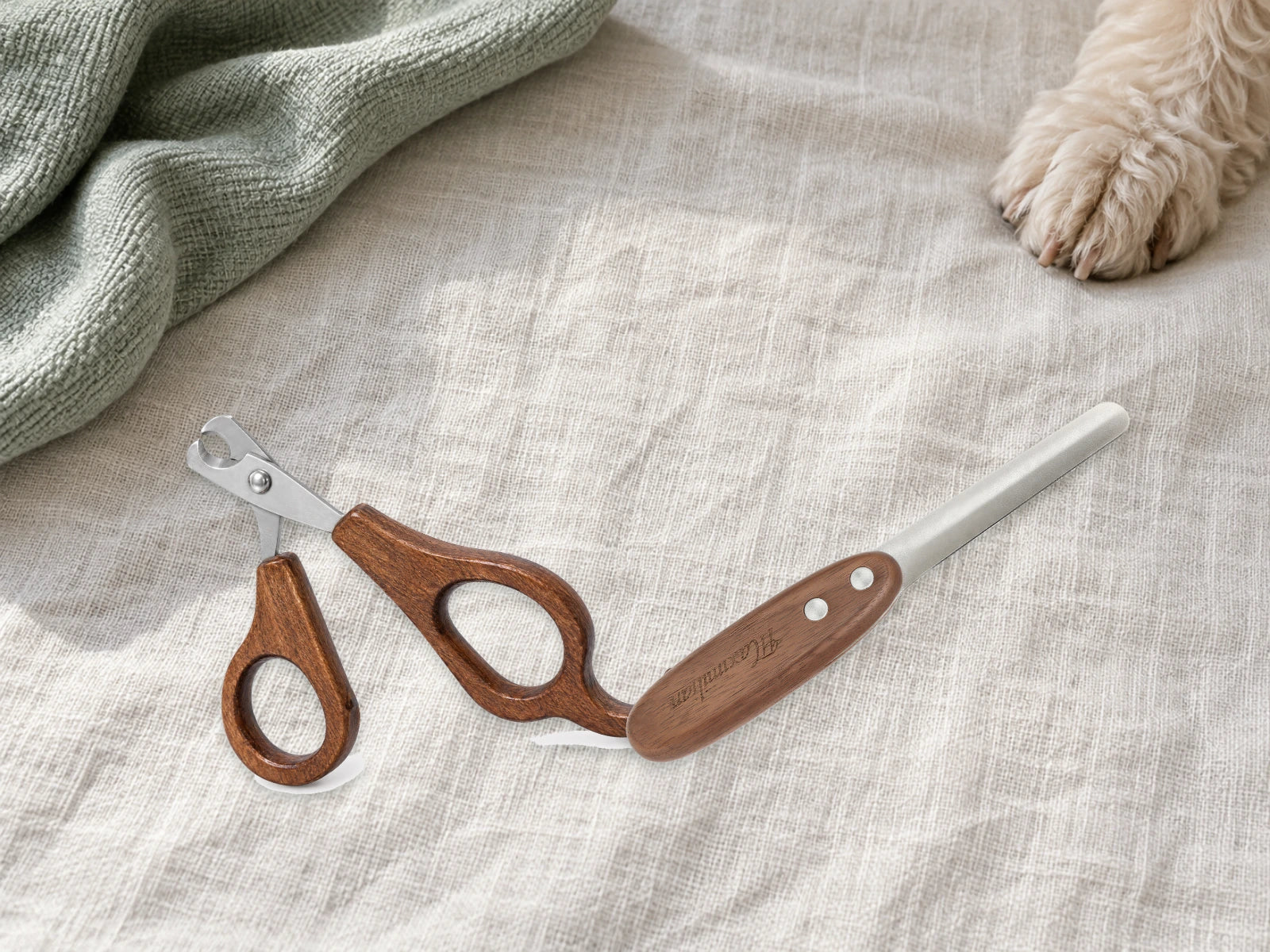 Wood-handled nail clippers and nail file on linen beside a dog paw